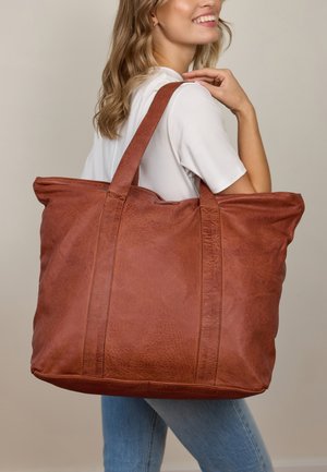 Brown leather tote bag with a soft texture and two sturdy straps, featuring visible stitching and a spacious design.