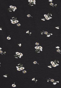 Svart tyg med ett blommönster som har vita prästkragar och gröna stjälkar, jämnt fördelade över ytan. Mjuk textur.