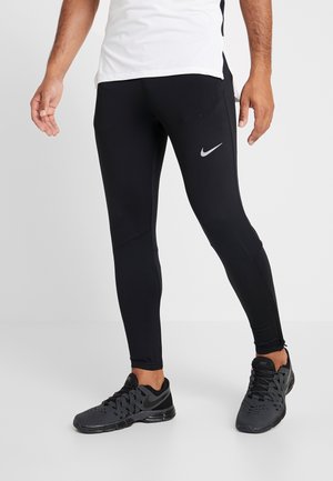Zwarte sportlegging met een nauwsluitend ontwerp, gemaakt van rekbaar materiaal, met een klein reflecterend Nike-logo op de linker dij.