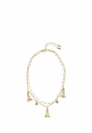 Gold-tone necklace featuring multiple chains with white beads, decorative tassels, and geometric accents. Adjustable clasp with extension chain.
