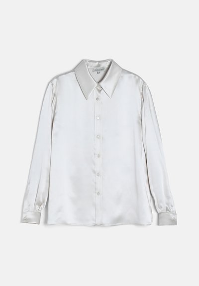 Chemise en satin blanc à manches longues, boutonnée, avec col large et pointu et poignets boutonnés, présentée sur un fond uni.