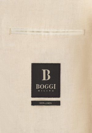 Tissu en lin beige avec détail de poche passepoilée, étiquette noire indiquant « B Boggi Milano » et petite étiquette mentionnant « 100 % lin ».