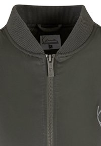 Graue Bomberjacke mit geripptem Kragen, Reißverschluss und dezentem Logodetail. Glatte Außenstruktur mit taillierter Passform. Größe S.