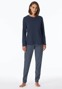 Marineblaues Langarmoberteil kombiniert mit marineblau-weiß gestreiften Schlafanzughosen. Baumwollmaterial, lockere Passform, elastische Bündchen an den Hosen und Rundhalsausschnitt.