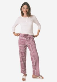 Pantaloni leggeri e patterned in rosa chiaro con disegni floreali; vita elasticizzata con cordoncino; abbinati a un top a maniche lunghe bianco.