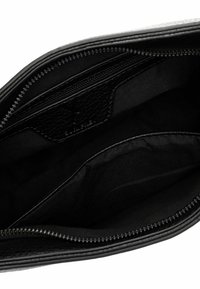 Svart läderhandväska inuti med slät tygfoder, som har en zippered ficka och fack för organisering, med en stilren design.