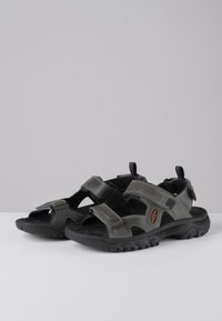 Gray outdoor sandals with adjustable Velcro straps, breathable mesh, textured black sole, and reinforced toe protection.