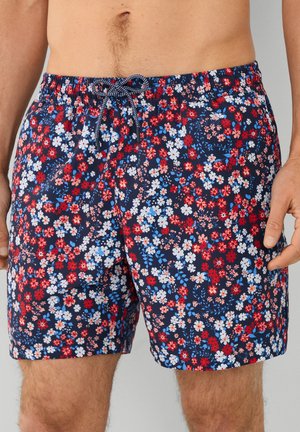 Marineblaue Badeshorts mit einem floralem Muster in Rot, Weiß und Blau. Elastischer Bund mit Kordelzug, mittellange Beinform, leichtes Material.
