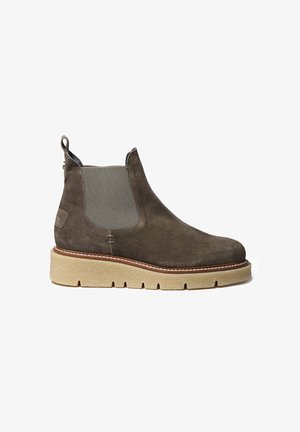 Bottines en suede gris foncé avec des panneaux latéraux élastiques, semelle beige texturée et coutures blanches contrastantes. Bout rond et languette à l'arrière.