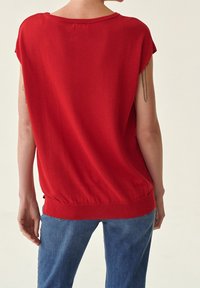 Rotes, gestricktes Oberteil mit kurzen Ärmeln und rundem Halsausschnitt. Hat einen gerippten Saum und eine lockere Passform, gefertigt aus weichem Stoff.