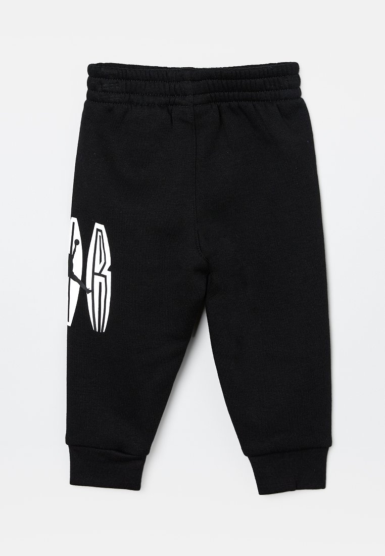 Pantalones de chándal negros hechos de algodón, con una cinturilla elástica, puños acanalados y un destacado diseño de logo blanco en un lado.