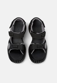 Sandali neri e grigi con cinturini in velcro regolabili, suole in gomma stampata e plantari imbottiti; design aperto per traspirabilità.