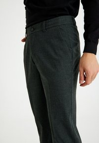 Heren donkergrijze broek van gestructureerde stof, met een vlakke voorkant, zijzakken en een knoopsluiting bij de tailleband.