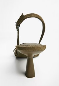 Sandalo con tacco alto in suede marrone, dotato di una fascia testurizzata e di un tacco a blocco. Presenta un design minimalista e un dettagli di fibbia regolabile.