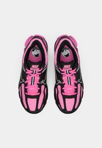 Pár ružovo-čiernych bežeckých topánok Nike Vomero 5 s ružovými šnúrkami a reflexnými detailmi, zobrazené zhora na bielom pozadí.