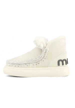 Botas de tobillo de ante blanco con un cuello con flecos, costuras decorativas y acentos plateados brillantes en el costado. Suela de goma, acabado texturizado.