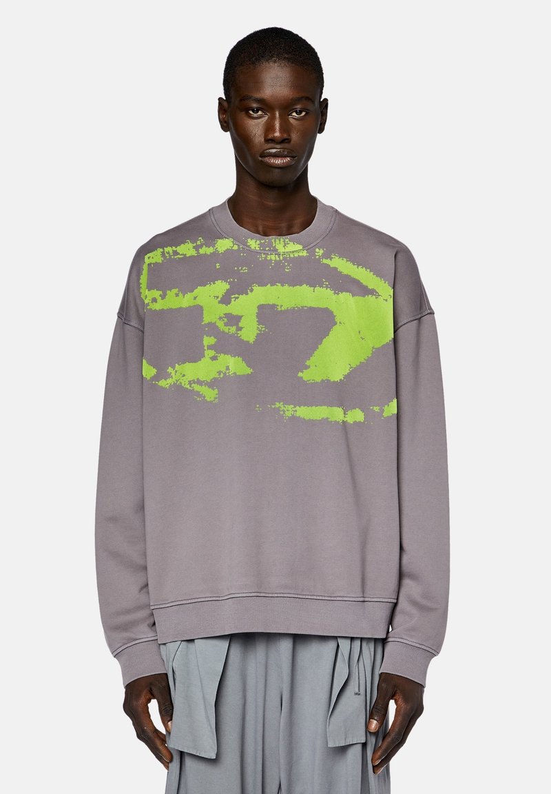 Sweatshirt gris avec un grand design graphique lime vert irrégulier. Présente un col rond et des poignets côtelés. Structure ample visible.