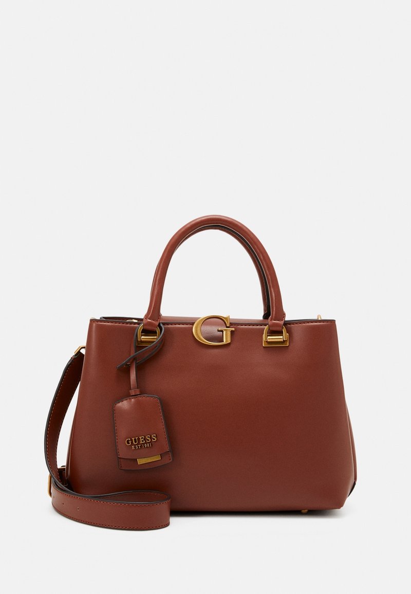 Sac à main en cuir marron avec ferrures dorées, présentant un logo "G" bien visible, deux poignées et une bandoulière amovible. Comprend une étiquette avec la marque.