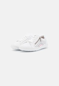 Baskets en cuir blanc avec un design perforé et des accents roses, dotées de lacets et d'une fermeture éclair sur le côté, avec une semelle en caoutchouc texturée.