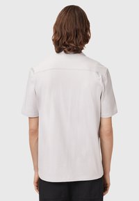 Short-sleeve light gray shirt with a smooth texture and subtle stitching detail on the back. Features a relaxed fit and classic collar.