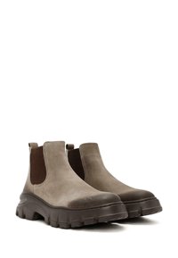 Bottes chelsea en daim marron, avec panneaux élastiques, bout rond et semelles en caoutchouc épaisses équipées d'un profond profil pour une meilleure adhérence.