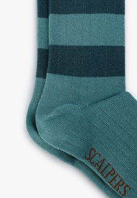 Calcetines a rayas en diferentes tonos de azul petróleo y marino, con textura de punto, puño acanalado y logo de "SCALPERS" en marrón en el tobillo.