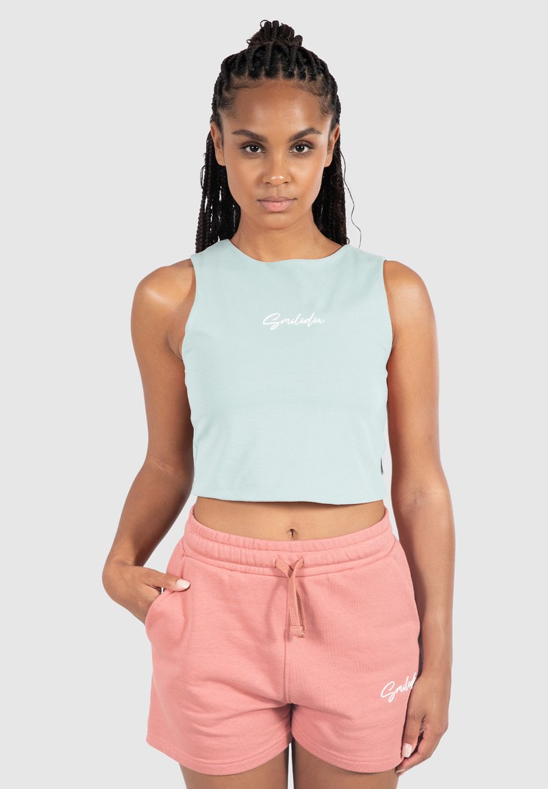 Mintgrøn cropped tanktop med hvidt logo på brystet, parret med lyserøde shorts med snoretræk, der har sidelommer og en blød tekstur.