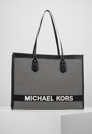 Torba typu tote z czarno-białym wzorem, z dwoma czarnymi uchwytami i napisem "MICHAEL KORS" w pogrubionych białych literach na przednim panelu.