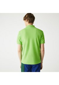 Kortärmad polo i klargrön, gjord av ett slätt material med krage. Sömlös baksidesdesign, rena kanter.