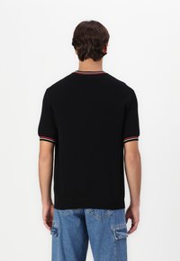 Black short-sleeve sweater with multi-colored ribbed crew neck, featuring red and green stripes on cuffs for accent. Textured fabric finish.