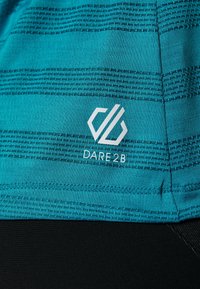 Tkanina w kolorze morskim z teksturowanymi poziomymi paskami i nadrukowanym białym logo "DARE 2B" na czarnym tle poniżej.