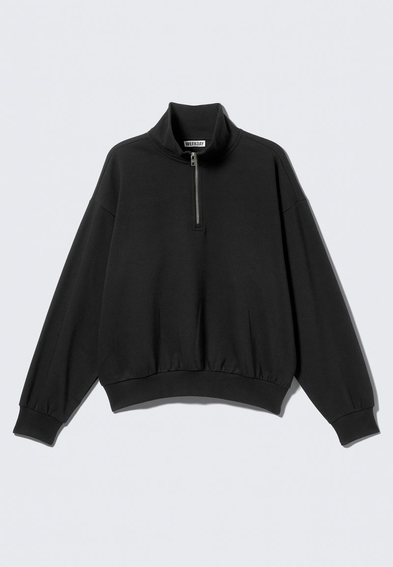 Sudadera negra con cuello alto y media cremallera, con hombros caídos y borde acanalado. Fabricada con un tejido suave y texturizado.