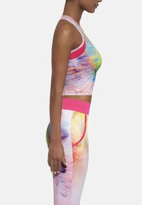 Kolorowy, dopasowany stanik sportowy i legginsy wykonane z elastycznej tkaniny. Stanik ma różowe akcenty; legginsy zdobione są żywym, abstrakcyjnym wzorem.