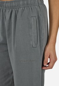 Γκρι παντελόνια φόρμας από μαλακό ύφασμα, με ελαστική μέση, διαγώνιες πλευρικές τσέπες και ανάγλυφο λογότυπο στο πλάι.