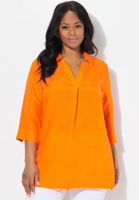 Oranje linnen tuniek met een V-hals, driekwartmouwen en een relaxte pasvorm. Heeft een subtiele middenplooi voor extra detail.