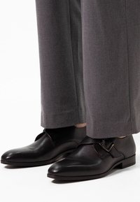 Zwarte leren schoenen met een spitse neus en een zijgespannetje. Draag ze met grijs taps toelopende broeken, die een gladde textuur en een minimaal ontwerp laten zien.