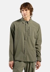 Grünes Langarmhemd aus leichtem Stoff, mit Knopfverschluss, Kragen und einer Brusttasche mit einem kleinen Reißverschlussdetail.