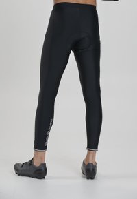 Schwarze Herren-Radsporttights mit gepolstertem Sitz, glattem Stoff, knöchellangem Design und reflektierendem "ENDURANCE"-Logo an der Seite.