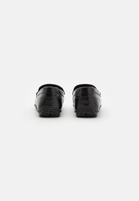 Scarpe nere in pelle con una finitura liscia, caratterizzate da un profilo basso e due bande orizzontali sulla parte superiore. Suola in gomma tassellata.