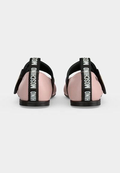 Paire de chaussures plates roses avec des brides noires au talon affichant le logo blanc Moschino, vues de dos sur fond blanc uni.
