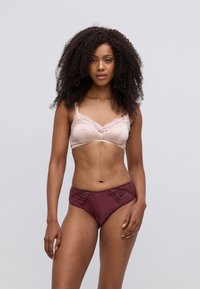 Csipkebetétes rózsaszín bralette, amelyet bordó, teljes takarású bugyival párosítottak, csipkebetétekkel, sima anyaggal és testhezálló fazonnal.