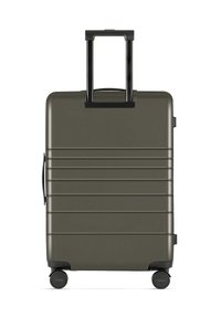 Harde koffer in matte olijfgroen met verticale ribbels, uitschuifbare zwarte handgreep en vier wielen voor gemakkelijke mobiliteit.