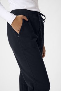 Černé bavlněné joggers s uvolněným střihem, bočními kapsami a šňůrkovým pasem. Hladká textura a minimalistický design.