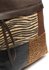 Hnědá kožená kabelka s patchworkovým designem, který zahrnuje zebrovanou část s chlupem, texturovaný černý krokodýlí vzor a skvrnité béžové akcenty.
