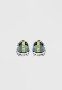 Πράσινα πάνινα παπούτσια με υφασμάτινους ταμπελέδες τακουνιού σε έντονο πράσινο χρώμα, λευκές λαστιχένιες σόλες και μαύρες λεπτομέρειες με το λογότυπο "Converse All Star".