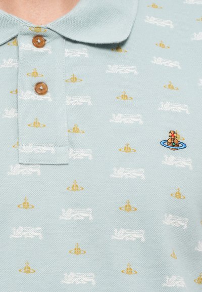 Cămașă polo de culoare albastru deschis, cu un tricot texturat, având un model general cu motive albe și aurii. Include un placket cu două nasturi și detalii brodate.