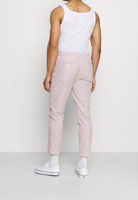 Gestreepte broeken in rood en wit met een slim fit en enkellengte. Voorzien van twee achterzakken en gecombineerd met witte sneakers en sokken.