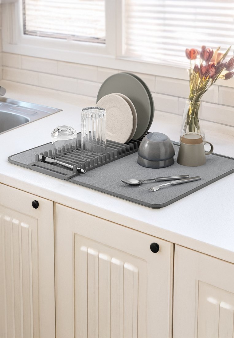 Graue Abtropfmatte mit vertikalen Fächern, die Teller, Gläser und Besteck hält. Weiche Textur und abgerundete Kanten. Einfaches, modernes Design.