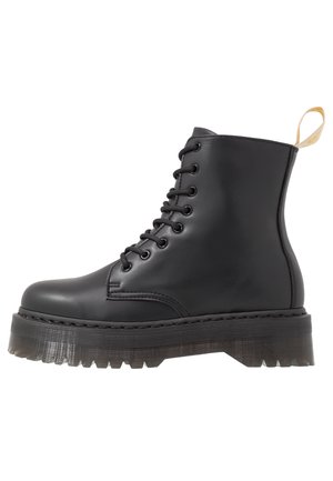Schwarze Leder-Ankle-Boots mit einer runden Zehenpartie, Schnürung auf der Vorderseite und einer klobigen, strukturierten Plateausohle. Mit einem kontrastierenden gelben Ziehschlaufe.