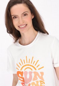 Witte t-shirt met een kleurrijke "SUNSHINE" grafiek in oranje en roze tinten, met zonnestraalaccenten boven de tekst. Gladde stoftextuur.